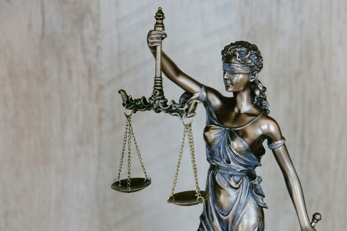 Lady Justice statue with scales against a warm background
